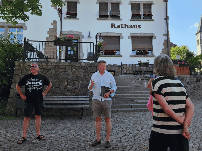 Die Teilnehmenden des Ortsteil-Dialogs stehen bei sonnigem Wetter auf dem Rathauspaltz in Altglashütten und diskutieren Zukunftspläne. Das Bild zeigt Bürgermeister Albrecht und Personen beim Ortsteildialog in Altglashütten vor dem Rathaus